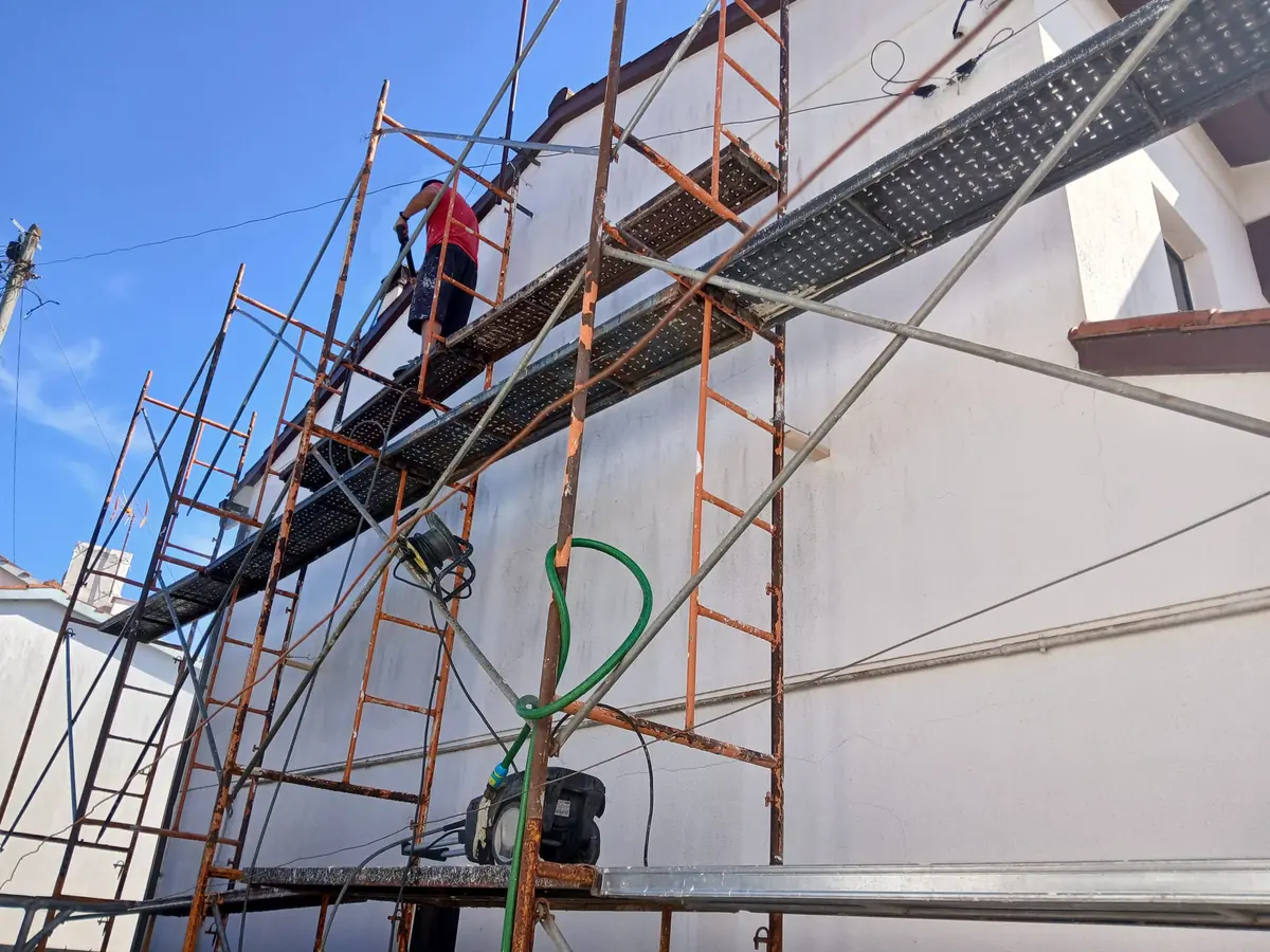 Andaimes montados na fachada de uma casa, com o equipamento de pintura.