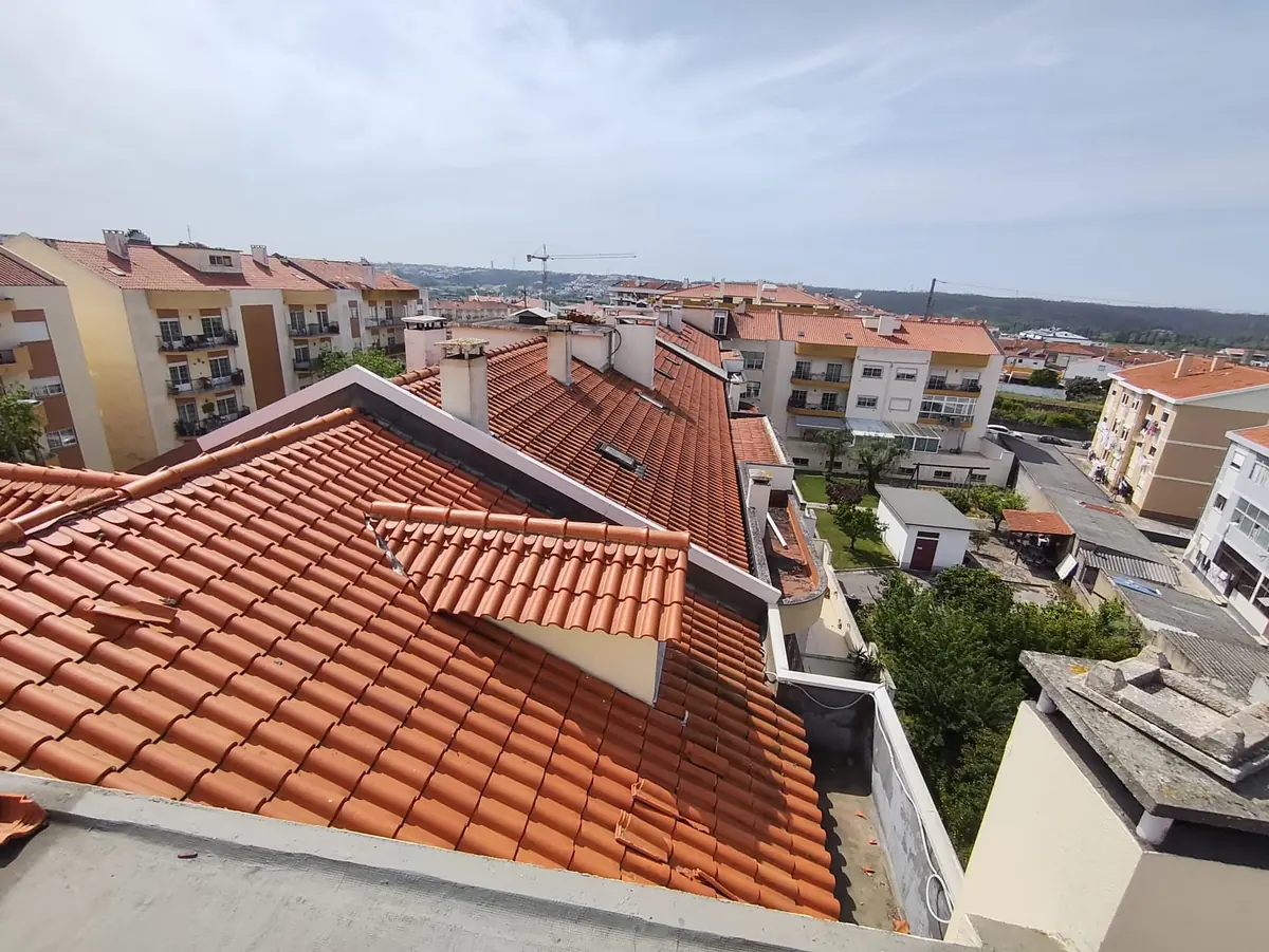 Telhado de telha cerâmica com trapeiras, numa zona de moradias.